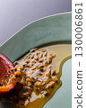 Half a passion fruit on a plate with fruit and juice spilling out 130006861