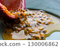 Half a passion fruit on a plate with fruit and juice spilling out 130006862