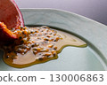 Half a passion fruit on a plate with fruit and juice spilling out 130006863