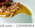 Half a passion fruit on a plate with fruit and juice spilling out 130006864