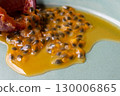 Half a passion fruit on a plate with fruit and juice spilling out 130006865