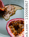 Half a passion fruit on a plate with fruit and juice spilling out 130006867