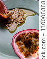 Half a passion fruit on a plate with fruit and juice spilling out 130006868