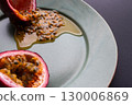 Half a passion fruit on a plate with fruit and juice spilling out 130006869