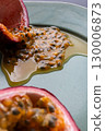 Half a passion fruit on a plate with fruit and juice spilling out 130006873