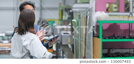A male business person and a female worker inspecting a factory 130007483
