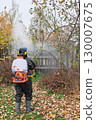 man in mask and overalls sprays garden with against pests in autumn. 130007675