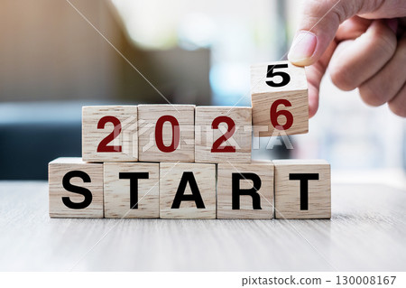 Businessman hand holding wooden cube with flip over block 2025 to 2026 Plans word on table background. Resolution, strategy, solution, goal, business and New Year holiday concepts 130008167