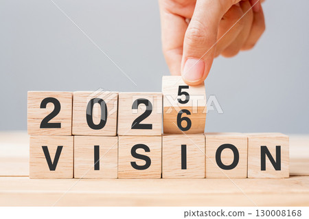 hand flipping block 2025 to 2026 VISION text on table. Resolution, strategy, goal, motivation, reboot, business and New Year holiday concepts 130008168