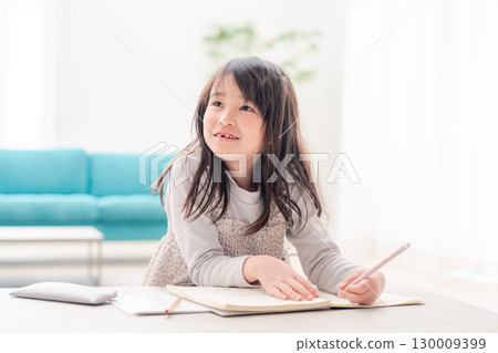 A girl in the lower grades of elementary school doing her homework alone at home A girl in the lower grades of elementary school doing her homework alone at home 130009399