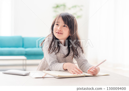 A girl in the lower grades of elementary school doing her homework alone at home 130009400