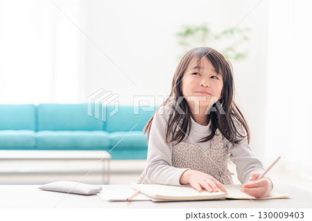 A girl in the lower grades of elementary school doing her homework alone at home 130009403