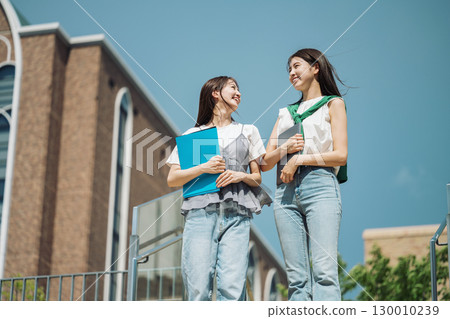 A female college student walking around the campus, chatting happily with her friends 130010239