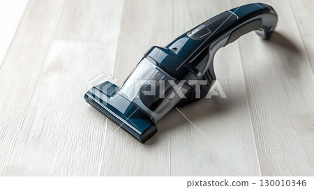 A blue vacuum cleaner with a black handle sits on a wooden floor 130010346