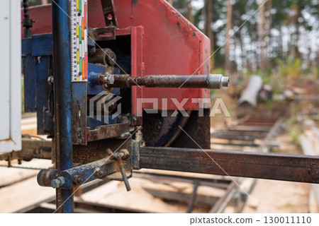 Close-up of machine for sawing pine logs at sawmill Close-up of machine for sawing pine logs at sawmill 130011110