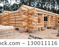 The construction site of a wooden house. Traditional log cabin built from wood logs on sunny summer day. 130011116