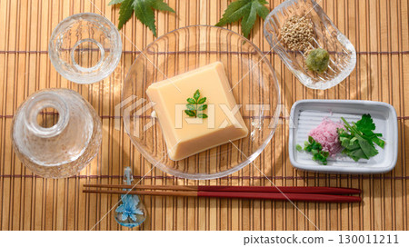 清爽夏日日式料理:雞蛋豆腐和佐料盛放在透明玻璃盤中。清爽優雅的菜餚形象。 清爽夏日日式料理:雞蛋豆腐和佐料盛放在透明玻璃盤中。清爽優雅的菜餚形象。 130011211