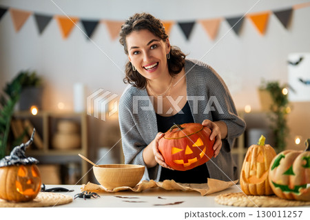 woman is carving pumpkin woman is carving pumpkin 130011257