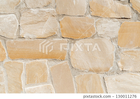 Antique ancient stone wall masonry texture background. Old wall made of beige stone blocks  130011276