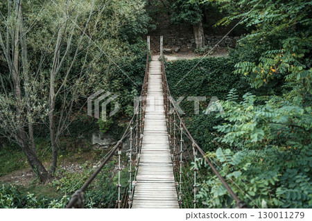 Old Suspension Bridge in the Forest. Adventure and Nature Concept Old Suspension Bridge in the Forest. Adventure and Nature Concept 130011279