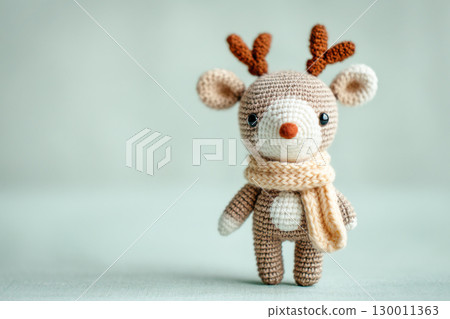 Adorable knitted reindeer toy wearing a cozy scarf, showcasing intricate craftsmanship and soft textures against a gentle pastel background 130011363