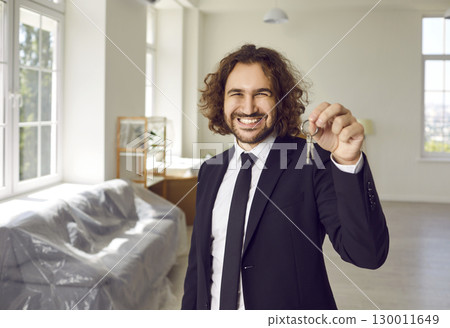 Portrait of a young happy smiling man with keys in his hands looking at camera in new house. Portrait of a young happy smiling man with keys in his hands looking at camera in new house. 130011649