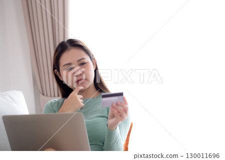 Young asian woman sitting on sofa using laptop computer shopping online with credit card. 130011696