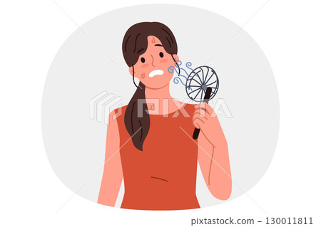 Woman uses electric fan to stop sweating and prevent exhaustion in hot summer weather 130011811