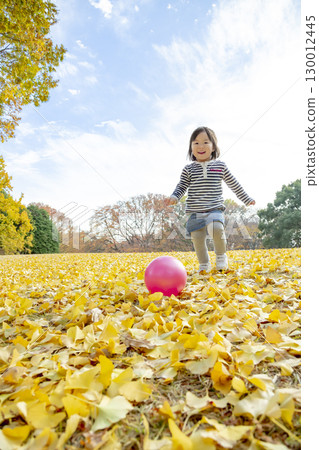 Girl playing in the park with yellow leaves 130012445