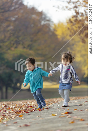 一個男孩和一個女孩在秋天落葉的公園玩耍 130012457