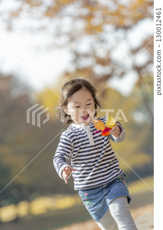 Girl playing in the park of autumn leaves 130012461