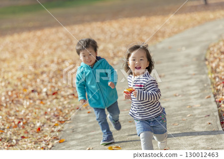 一個男孩和一個女孩在秋天落葉的公園玩耍 130012463