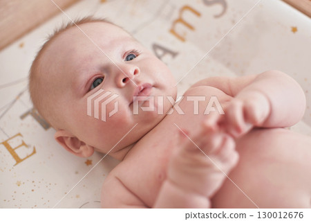4 months old infant baby boy at changing table, detail on his head 130012676