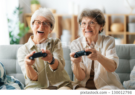 Two senior women playing console game Two senior women playing console game 130012798