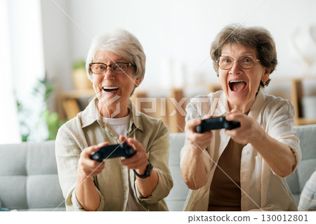 Two senior women playing console game Two senior women playing console game 130012801