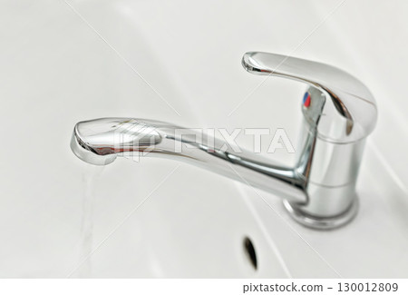 Chrome faucet tap with water flowing, closeup detail 130012809