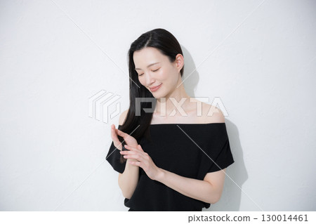 A woman doing hair care for the ends of her hair. Image of treatment and split ends. 130014461
