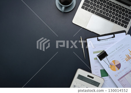 Top view of office desk with laptop, calculator, financial reports, and coffee cup on desk 130014552
