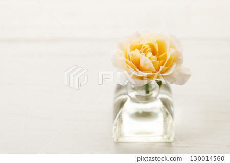 Yellow beautiful rose in glass vase on wooden table. Selective focus. Yellow beautiful rose in glass vase on wooden table. Selective focus. 130014560