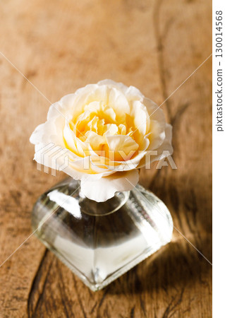 Yellow beautiful rose in glass vase on wooden table. Selective focus. 130014568