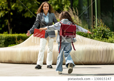 Joyful little girl running with open arms towards her mother 130015147