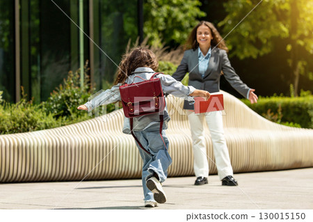 Joyful little girl running with open arms towards her mother 130015150