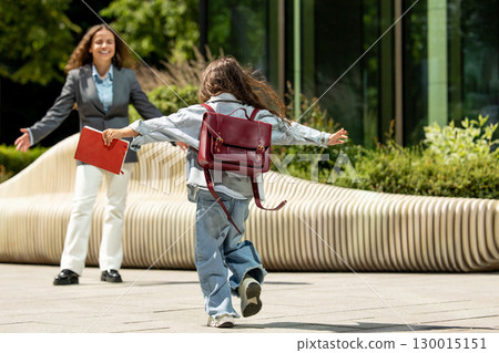 Joyful little girl running with open arms towards her mother 130015151