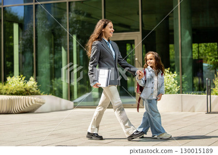 Working mom and child walking together after school in urban setting Working mom and child walking together after school in urban setting 130015189