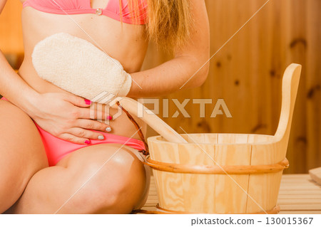 Closeup of woman in sauna with exfoliating glove. Closeup of woman in sauna with exfoliating glove. 130015367