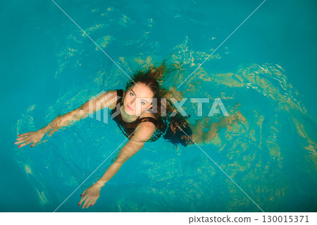 Woman floating relaxing in swimming pool water. Woman floating relaxing in swimming pool water. 130015371