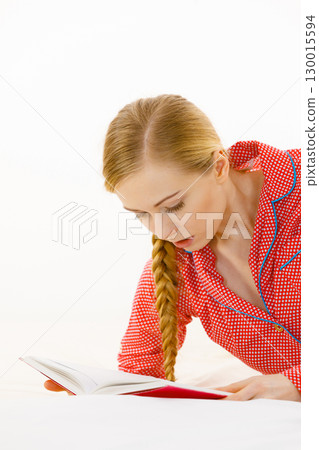Woman relaxing in bed reading book 130015594