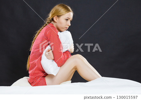 Sad depressed girl in bed gripping pillow Sad depressed girl in bed gripping pillow 130015597