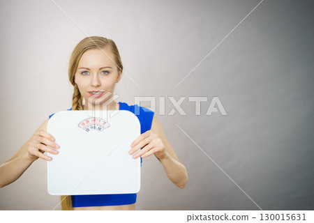Teenage woman holding bathroom scale machine Teenage woman holding bathroom scale machine 130015631