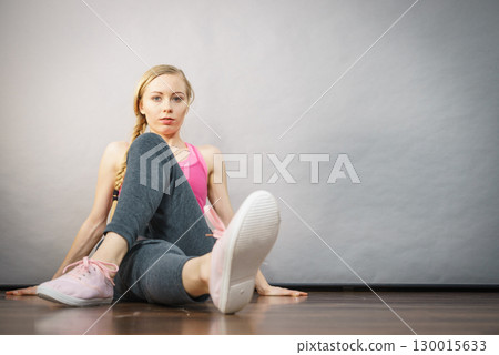 Woman in sportswear sitting on ground 130015633